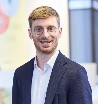 Christopher Büchel schaut nach vorne und lächelt.